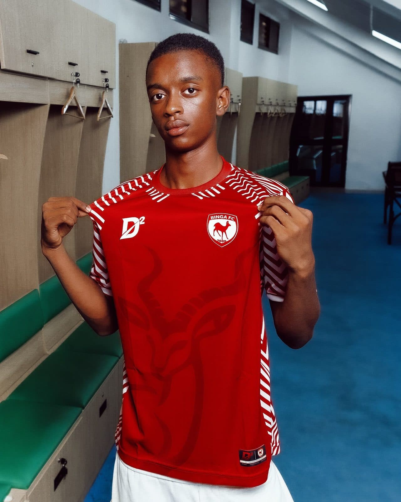 Joueur présentant le maillot domicile BINGA FC dans un vestiaire